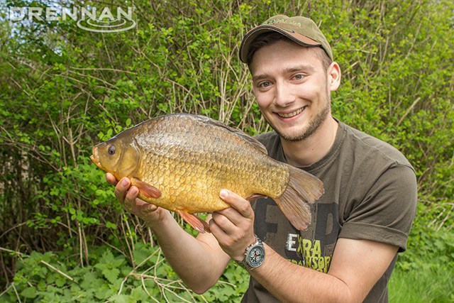 The fisherman takes a crucian fish from a fishing hook, visible